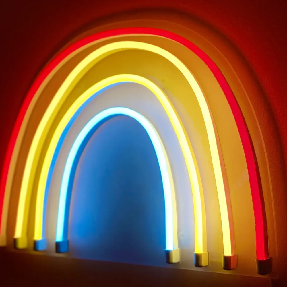 Glowing neon rainbow light on a red wall